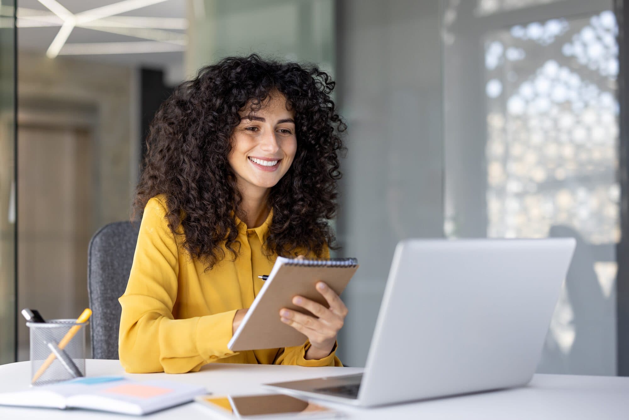 A woman with a tablet smiles at her desk
