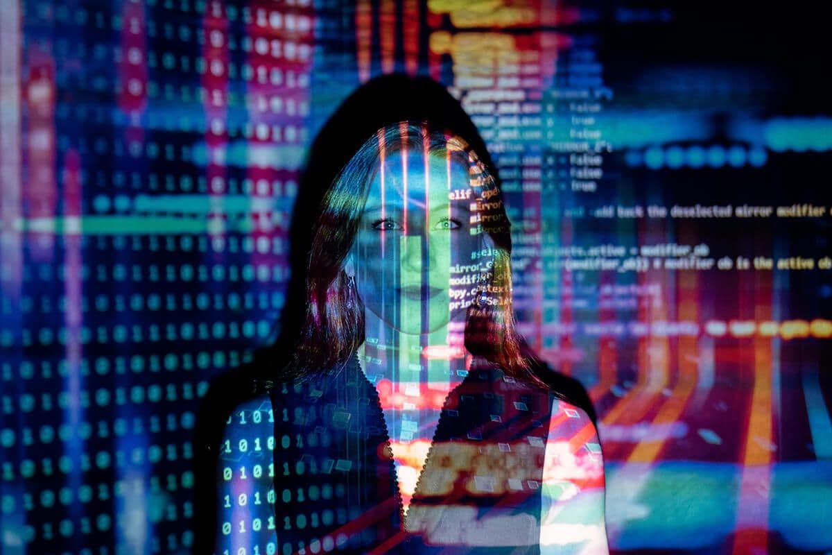 Woman standing in front of a projection of code, numbers and colors. She's giving a presentation on AI in HR.
