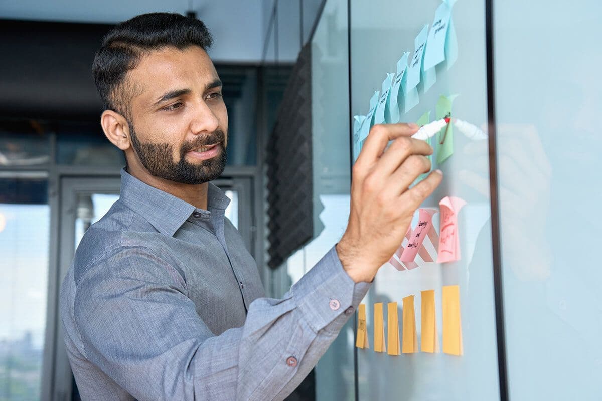 Employee organizing professional goals with sticky notes on a glass wall