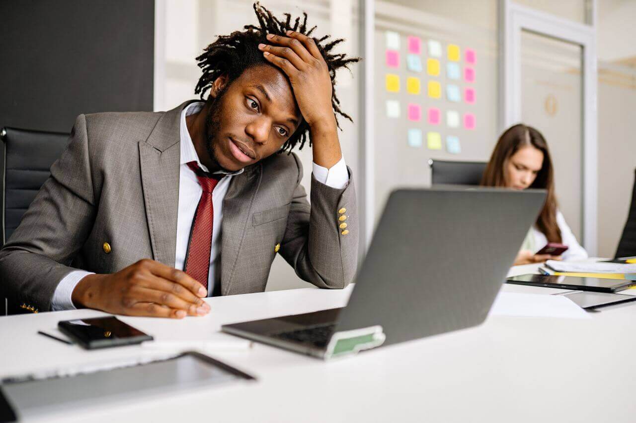 A stressed-looking professional looks at his laptop