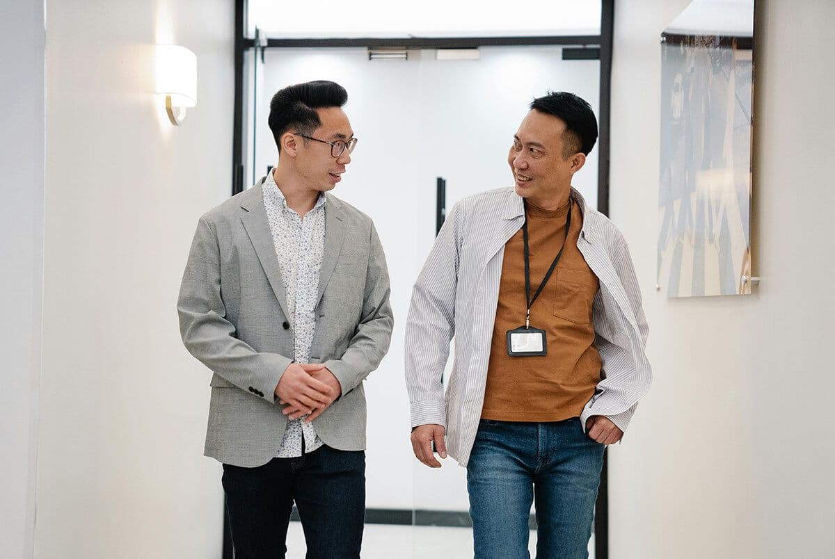 Two men walking in an office hallway discussing building a mentorship culture