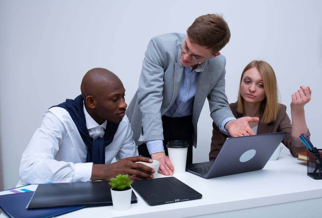 Three colleagues argue while sitting at a conference table